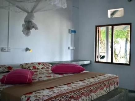 a bedroom with a bed with pink pillows and a window at The Alpha Monkey hotel & Tree house in Tangalle