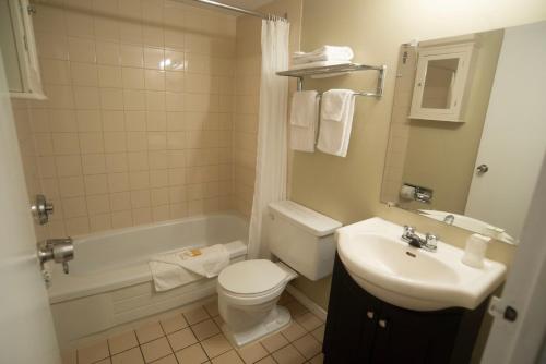 a bathroom with a toilet and a sink and a tub at Midtown Inn in Saskatoon