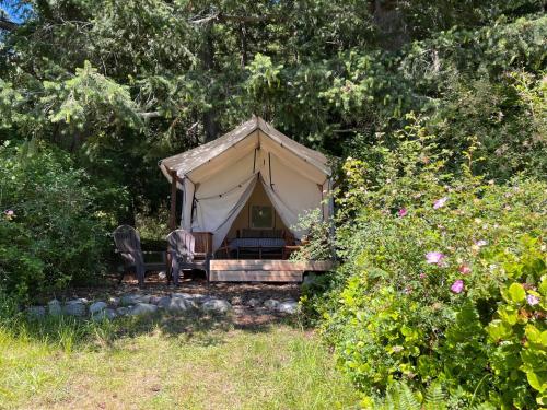 a tent with a bed and chairs in a garden at Lopez Farm Cottages & Tent Camping in Lopez