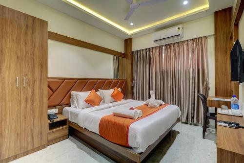 a bedroom with a bed and a desk and a television at Hotel Archith in Navi Mumbai