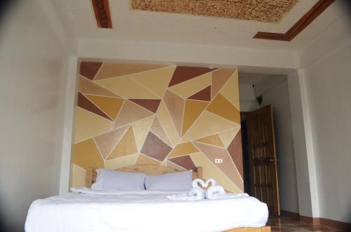 a bedroom with a bed with a geometric wall at Batad Roberto's Abung Inn and Restaurant in Banaue