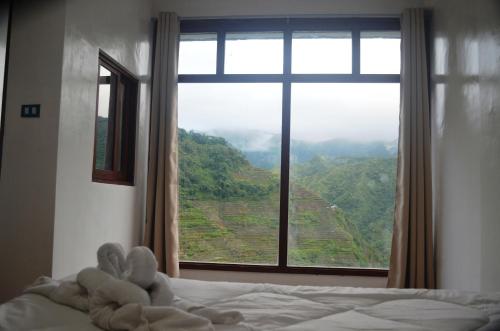 a bed with a window with a view of a mountain at Batad Roberto's Abung Inn and Restaurant in Banaue