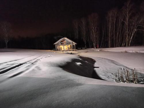 a house in the middle of a snow covered field at Sodyba vienkiemyje "Šeimos slėnis" in Kupiškis