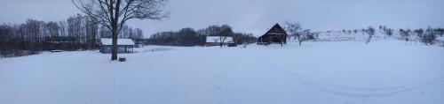 a field covered in snow with a house in the background at Sodyba vienkiemyje "Šeimos slėnis" in Kupiškis