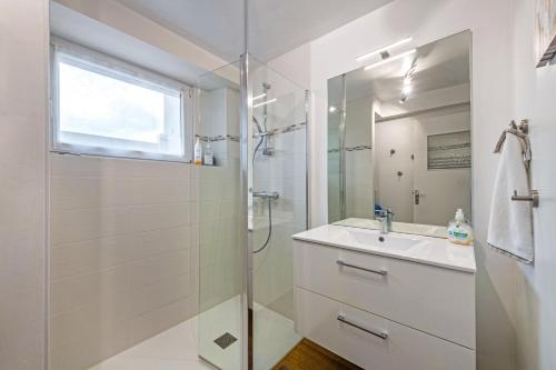 y baño blanco con lavabo y ducha. en Appartement 85m2 à 2kms plage en Kerlouan