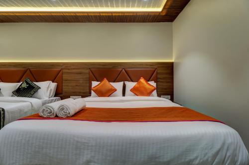 a bedroom with two beds with orange and white pillows at Hotel Archith in Navi Mumbai