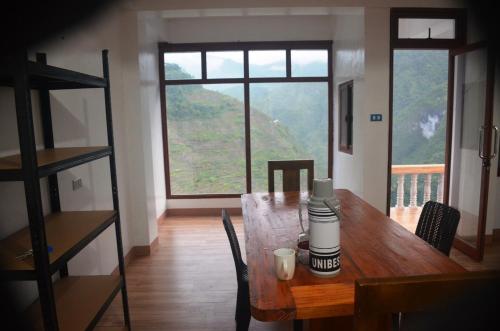 a dining room with a wooden table and a large window at Batad Roberto's Abung Inn and Restaurant in Banaue