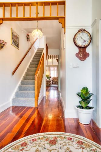 a living room with stairs and a clock on the wall at Villa near CBD and Globox Arena in Hamilton