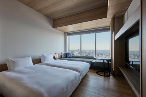a hotel room with two beds and a large window at The Royal Park Hotel Iconic Nagoya in Nagoya