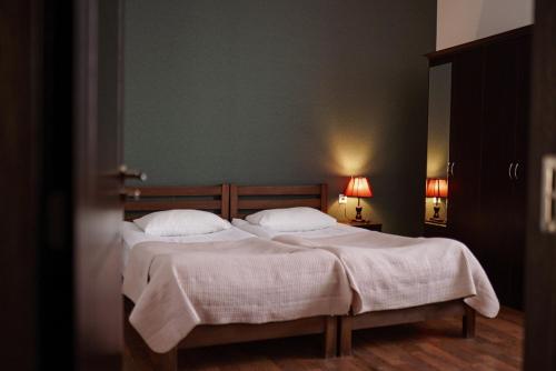 a bedroom with two beds with white sheets and two lamps at Hotel Starry Night in Stepantsminda