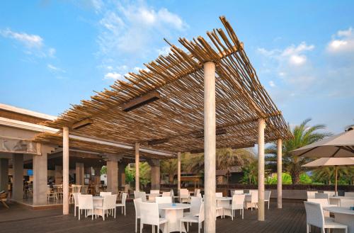 a pavilion with white tables and chairs and an umbrella at Lovina Beach Club & Resort in Lovina