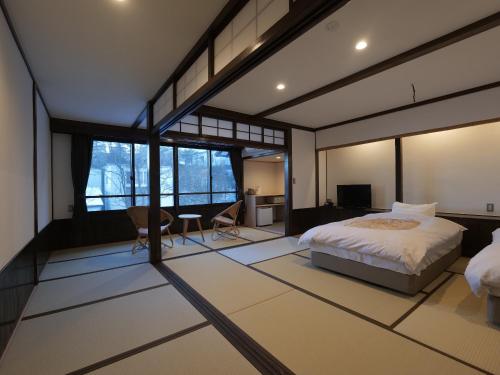 a bedroom with a bed in a room with windows at Kusatsu Onsen Kusatsu Hotel1913 in Kusatsu