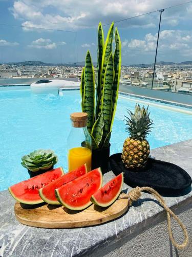 a tray of watermelon slices on a cutting board next to a pool at NEW 2BD APRT with SHARED ROOFTOP POOL E2 in Athens