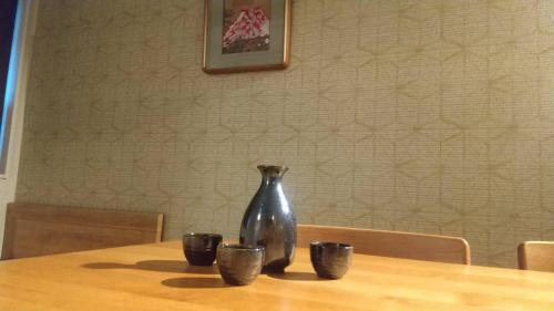 a vase sitting on top of a wooden table with cups at Higashiyama Chitaru in Kanazawa in Kanazawa