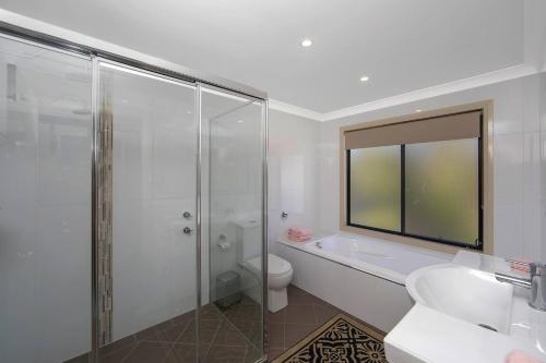a bathroom with a shower and a toilet and a sink at Easygoing Poolside Relaxation on Wyong River in Tuggerah