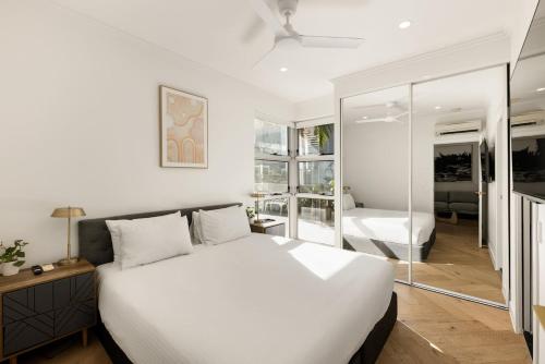 a bedroom with a large white bed and a mirror at 'The Cordelia' Sweeping South Brisbane Style in Brisbane