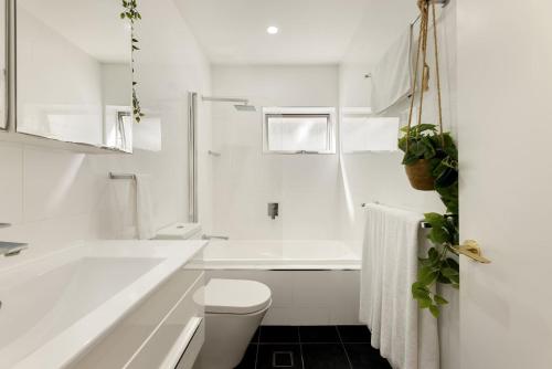 a white bathroom with a tub and a toilet at 'The Cordelia' Sweeping South Brisbane Style in Brisbane