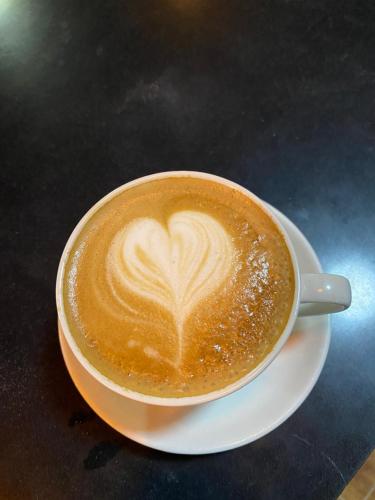 a cup of coffee sitting on a plate on a table at The Garden Place Hotel in Ruhengeri
