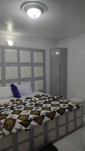 a bedroom with a bed with a quilt on it at WHITE EMIRATES HOTEL AND APARTMENT in Akinde