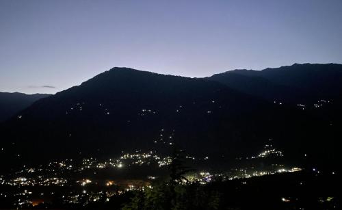 a view of a city from a mountain at night at MANDAP COTTAGE & CAFE in Nagar