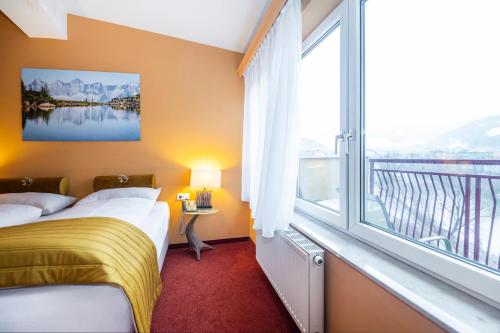 a hotel room with two beds and a large window at Hotel Landskron in Bruck an der Mur