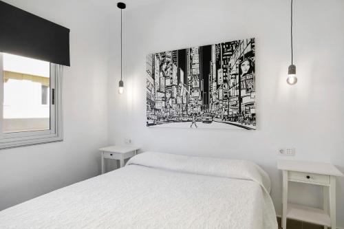 a bedroom with a white bed and a painting on the wall at Apartamento Kalma in Las Eras