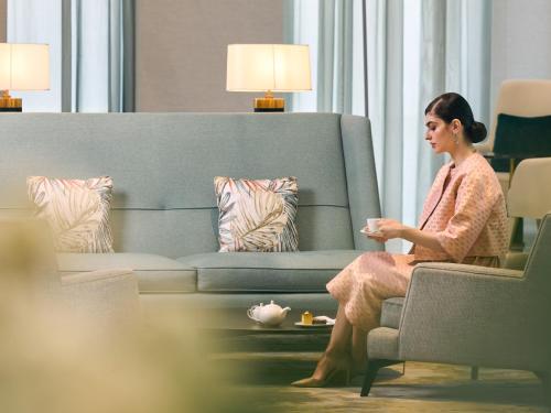 a woman sitting on a couch playing a video game at Fairmont Ramla Serviced Residences in Riyadh