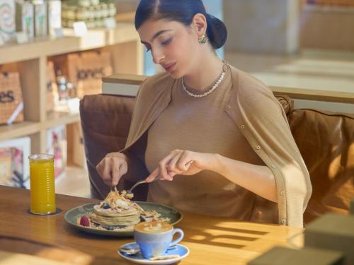 a woman sitting at a table with a plate of food at Fairmont Ramla Serviced Residences in Riyadh