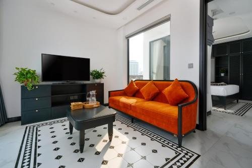 a living room with an orange couch and a tv at The Galaxy Home Doi Can Hotel and Apartment in Hanoi
