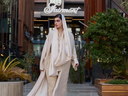 a woman walking down a street wearing a white robe at Fairmont Ramla Serviced Residences in Riyadh