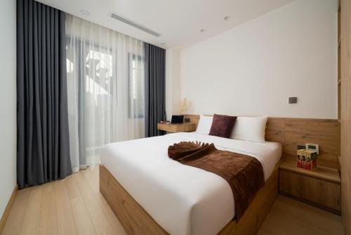 uma grande cama branca num quarto com uma janela em The Galaxy Home Doi Can Hotel and Apartment em Hanói