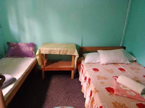 een kamer met twee bedden en een tafel erin bij Batad Viewpoints Guesthouse and Restaurants in Banaue
