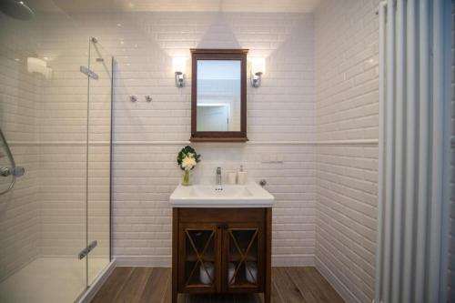 ein weißes Badezimmer mit einem Waschbecken und einem Spiegel in der Unterkunft Maya's Flats & Resorts 57 - Szafarnia in Danzig