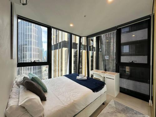 een slaapkamer met een bed en een groot raam bij Avant CBD Cozy & Spacious 2BR Residences in Melbourne
