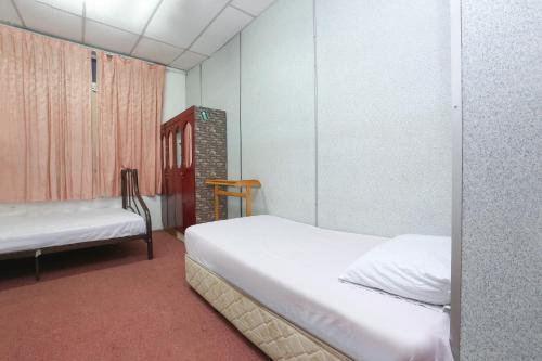 um pequeno quarto com 2 camas e uma janela em OYO 89755 D&d Budget Inn em Kota Bharu