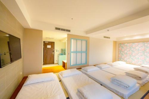 a bedroom with four white beds and a television at Kenting Long Beach Hotel in Checheng