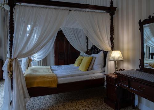 a bedroom with a canopy bed with yellow pillows at Hotel Dębowy Biowellness & SPA Góry Sowie in Bielawa