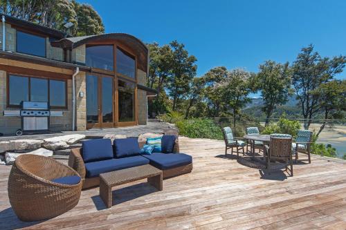 a patio with a couch and a table and chairs at Tokongawa Retreat in Kaiteriteri
