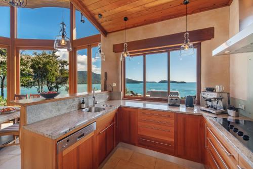 a kitchen with wooden cabinets and a view of the ocean at Tokongawa Retreat in Kaiteriteri