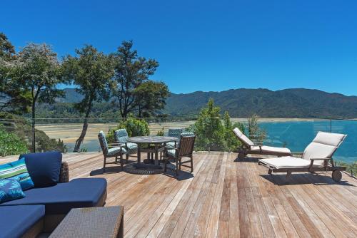 a patio with a table and chairs and a view of the water at Tokongawa Retreat in Kaiteriteri