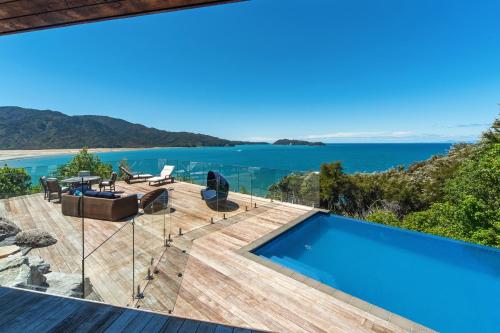 a house with a swimming pool and a view of the ocean at Tokongawa Retreat in Kaiteriteri
