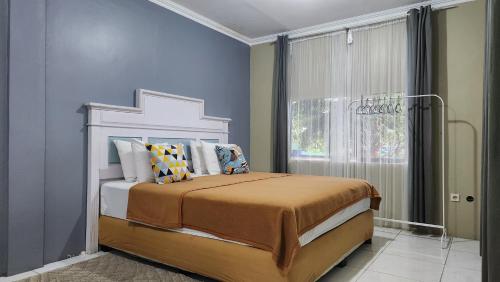 a bedroom with a bed with blue walls and a window at Alessandra Villa in Lembang