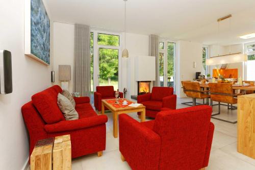 uma sala de estar com cadeiras vermelhas e uma mesa em Lotsenstieg 13a em Ostseebad Karlshagen