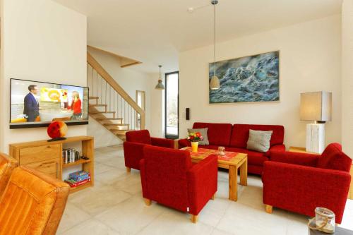 a living room with a red couch and red chairs at Lotsenstieg 13a in Ostseebad Karlshagen