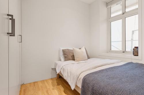 Habitación blanca con cama y ventana en Dinbnb Apartments I 500m to Bryggen, en Bergen