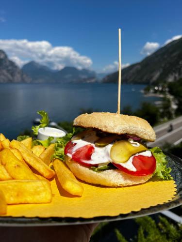 a sandwich and french fries on a plate next to a body of water at Wind Hotel in Malcesine