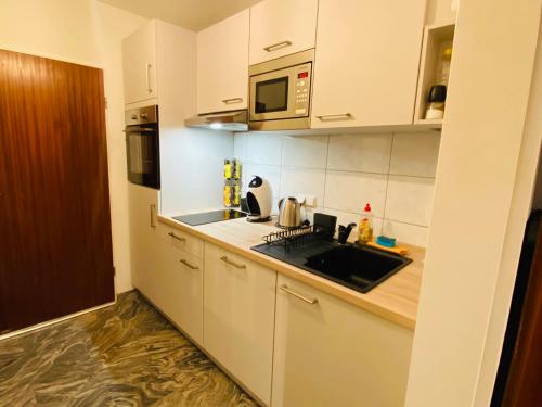 eine weiße Küche mit einer Spüle und einer Mikrowelle in der Unterkunft Schönes Wohnen in Groß-Buchholz - Zentral+Modern in Hannover