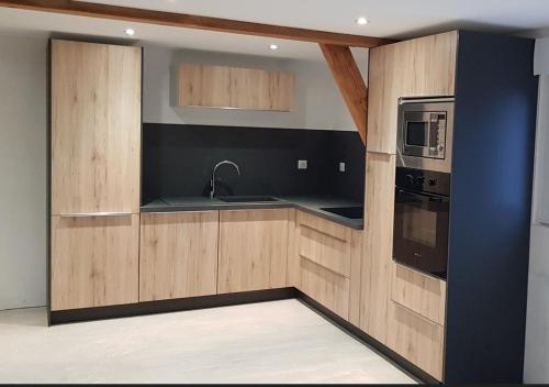 a kitchen with wooden cabinets and a sink and a microwave at La grange de LIZ&EL in Osthouse