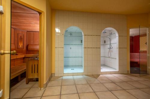 uma casa de banho com 2 cabinas de duche ao nível do chão com portas de vidro em Hotel Landskron em Bruck an der Mur