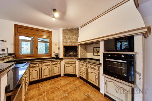 a large kitchen with wooden cabinets and appliances at Can Noguer Chalet de Lujo en Escaldes ,vistas panorámicas, jacuzzi in Escaldes-Engordany